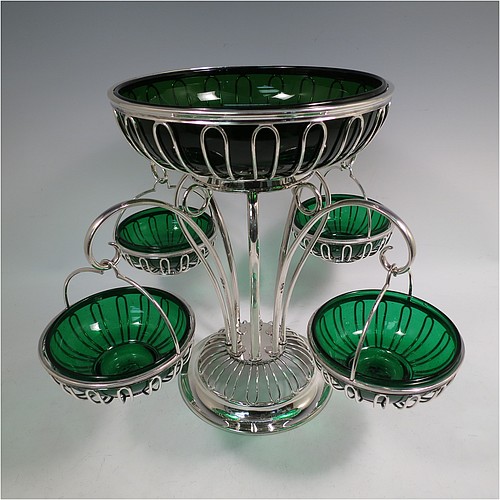 A very handsome and unusual Antique Edwardian Sterling Silver table Epergne centrepiece in an Art Nouveau style, having a removable central round wire-work basket and four matching removable swing baskets on side arms, all with dark green glass liners, and sitting on a spreading round base. Made by William Hutton of London in 1910. The dimensions of this fine hand-made antique silver Epergne table centrepiece are height 29 cms (11.5 inches), width across arms 38 cms (15 inches), and it weighs a total of approx. 1,954g (63 troy ounces)    