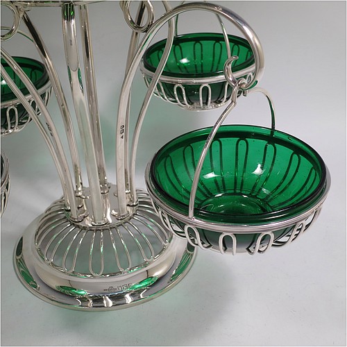 A very handsome and unusual Antique Edwardian Sterling Silver table Epergne centrepiece in an Art Nouveau style, having a removable central round wire-work basket and four matching removable swing baskets on side arms, all with dark green glass liners, and sitting on a spreading round base. Made by William Hutton of London in 1910. The dimensions of this fine hand-made antique silver Epergne table centrepiece are height 29 cms (11.5 inches), width across arms 38 cms (15 inches), and it weighs a total of approx. 1,954g (63 troy ounces)    