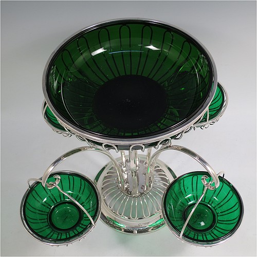 A very handsome and unusual Antique Edwardian Sterling Silver table Epergne centrepiece in an Art Nouveau style, having a removable central round wire-work basket and four matching removable swing baskets on side arms, all with dark green glass liners, and sitting on a spreading round base. Made by William Hutton of London in 1910. The dimensions of this fine hand-made antique silver Epergne table centrepiece are height 29 cms (11.5 inches), width across arms 38 cms (15 inches), and it weighs a total of approx. 1,954g (63 troy ounces)    