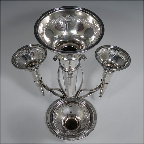 A Sterling Silver flower vase epergne center-piece, having four removable flower vases with hand-pierced top borders, with a central larger vase and three smaller side vases, all sitting on a pedestal base with wire-work scroll holders and applied reed-edged borders. Made by Henry Matthews of Birmingham in 1922. The dimensions of this fine hand-made sterling silver flower epergne are height 28 cms (11 inches), spread across vases 24 cms (9.5 inches), and it weighs approx. 645g (21 troy ounces).    