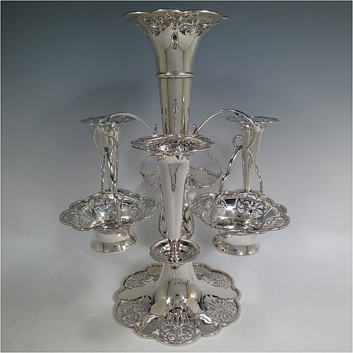 A very pretty Antique Edwardian Art Nouveau Sterling Silver table Epergne centrepiece, having a central large flower vase surrounded by three smaller vases and three removable swing-handled bowls, all with hand-pierced floral decoration, and sitting on a spreading lobed foot. Made by Fattorini and Sons of Birmingham in 1910/11. The dimensions of this fine hand-made antique silver Epergne table centrepiece are height 38.5 cms (15 inches), width 29 cms (11.5 inches), and it weighs a total of approx. 1,708g (55 troy ounces)    