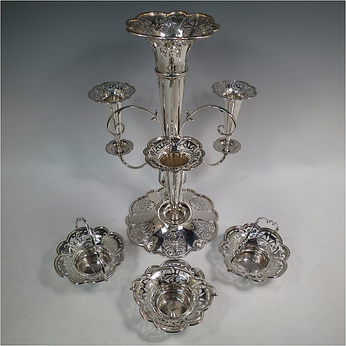 A very pretty Antique Edwardian Art Nouveau Sterling Silver table Epergne centrepiece, having a central large flower vase surrounded by three smaller vases and three removable swing-handled bowls, all with hand-pierced floral decoration, and sitting on a spreading lobed foot. Made by Fattorini and Sons of Birmingham in 1910/11. The dimensions of this fine hand-made antique silver Epergne table centrepiece are height 38.5 cms (15 inches), width 29 cms (11.5 inches), and it weighs a total of approx. 1,708g (55 troy ounces)    