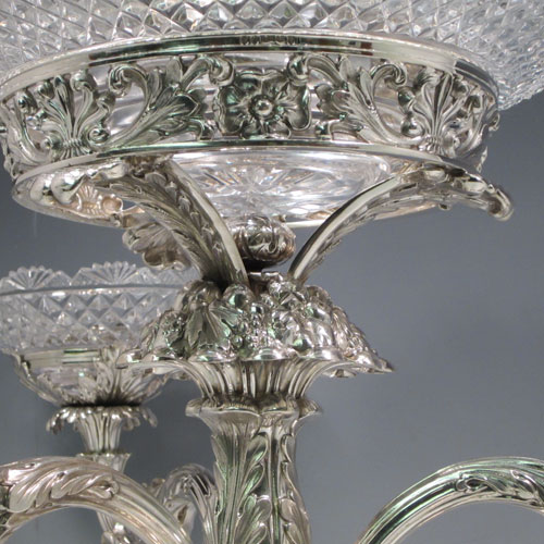 Antique Georgian sterling silver epergne centerpiece, having four hand-cut crystal bowls including a large central bowl for flowers or fruit and three smaller bowls for sweets or nuts, with each arm being removable, and all sitting on a very handsome base with hand-chased anthemion leaf and scroll work. Made by the famous silversmith Matthew Boulton of Birmingham in 1817. The dimensions of this fine hand-made silver center-piece are height 38 cms (15 inches), spread across arms 51 cms (20 inches), and it weighs approx. 2,820g (91 troy ounces).