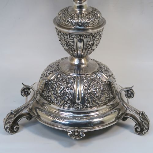 A very pretty Antique Victorian Sterling Silver table Epergne centrepiece, having a central cut crystal flower vase mounted above a matching round fruit bowl, all sitting on a lower silver body with hand-chased floral decoration, and three cast foliate feet. This beautiful silver and crystal epergne was made by Steven Smiley of London in 1876. The dimensions of this fine hand-made antique silver and crystal Epergne table centerpiece are height 53 cms (21 inches), and diameter of bowl 27 cms (10.5 inches),   