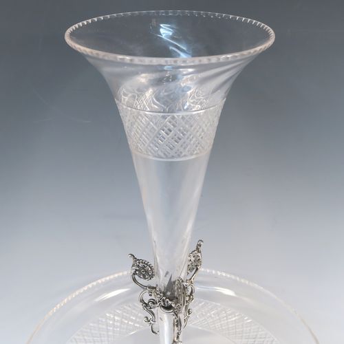 A very pretty Antique Victorian Sterling Silver table Epergne centrepiece, having a central cut crystal flower vase mounted above a matching round fruit bowl, all sitting on a lower silver body with hand-chased floral decoration, and three cast foliate feet. This beautiful silver and crystal epergne was made by Steven Smiley of London in 1876. The dimensions of this fine hand-made antique silver and crystal Epergne table centerpiece are height 53 cms (21 inches), and diameter of bowl 27 cms (10.5 inches),   