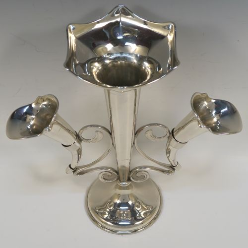 A pretty Antique Sterling Silver flower vase epergne center-piece in a plain round style, having two removable side flower vases connected to a central larger vase with scroll wire-work, and all sitting on a plain round pedestal base. This beautiful antique silver flower epergne was made by Joseph Gloster of Birmingham in 1913. The dimensions of this fine hand-made sterling silver flower centre-piece epergne are height 26 cms (10.25 inches), spread across vases 25.5 cms (10 inches), and it weighs approx. 465g (15 troy ounces).   