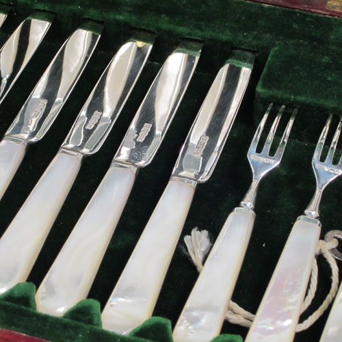 Antique Edwardian sterling silver and mother-of-pearl handled fruit set for twelve people. Having tapering bladed knives with serrated points and three-prong forks, all fitted into an original presentation box with dark green velvet interior. Made by Henry Atkins of Sheffield in 1910. The dimensions of this fine hand-made silver fruit service are length of knife 18 cms (7 inches), and the length of the fork 14.5 cms (5.75 inches). Please note that the brass plaque on top of the box lid is monogrammed.