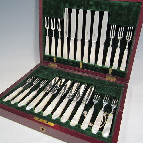 Antique Edwardian sterling silver and mother-of-pearl handled fruit set for twelve people. Having tapering bladed knives with serrated points and three-prong forks, all fitted into an original presentation box with dark green velvet interior. Made by Henry Atkins of Sheffield in 1910. The dimensions of this fine hand-made silver fruit service are length of knife 18 cms (7 inches), and the length of the fork 14.5 cms (5.75 inches). Please note that the brass plaque on top of the box lid is monogrammed.