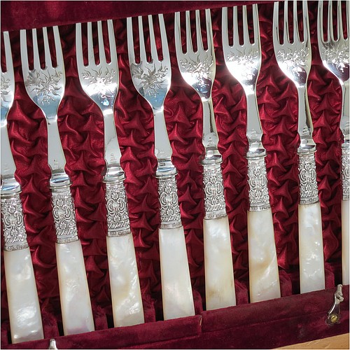 An Antique Victorian silver-plated and mother-of-pearl handled fruit set for twelve people, having hand-engraved tapering bladed knives and four-prong forks with floral decoration, with large hand-chased silver ferrules connecting the mother-of-pearl handles, all fitted into their original maroon satin and velvet-lined presentation box. The ferrules are of hallmarked sterling silver and are made by John Sanderson of Sheffield in 1897. The dimensions of this fine hand-made antique silver fruit service are length of knife 21 cms (8.25 inches), and the length of the fork 17.5 cms (7 inches).   