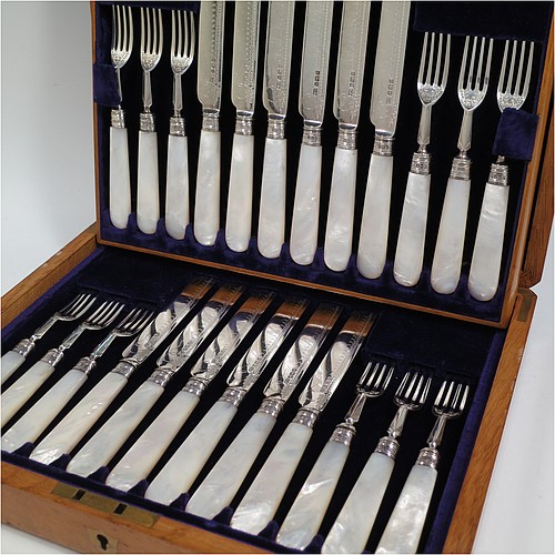 An Antique Edwardian Sterling Silver and mother-of-pearl handled fruit set for twelve people. Having straight-sided rounded-end blade knives, and four-prong forks, with hand-engraved floral decoration, and reed-work ferrules, all fitted into an original presentation box with dark blue velvet interior. Made by George Hancock of Sheffield in 1908. The dimensions of this fine hand-made antique silver fruit service are length of knife 19 cms (7.5 inches), and the length of the fork 15 cms (6 inches).   