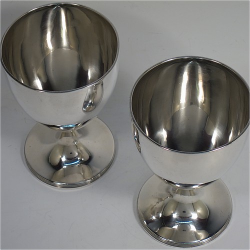 A very handsome pair of Antique Georgian Sterling Silver goblets, having plain round bodies with tapering sides, and sitting on pedestal feet with reeded borders. Made by John Robins of London in 1800. The dimensions of this fine hand-made pair of antique silver goblets are height 12 cms (4.75 inches), diameter at top 8 cms (3 inches), and the total weight is approx. 384g (12.4 troy ounces).   