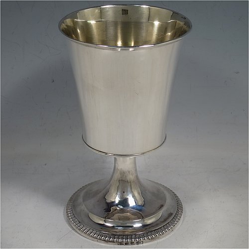 An Antique Georgian Sterling Silver wine goblet, having a plain round tapering body with straight sides, an applied reeded top border, and sitting on a pedestal foot with an applied straight gadroon edge. Made by Henry Nutting & Robert Hennell of London in 1809. The dimensions of this fine hand-made antique silver goblet are height 15 cms (6 inches), diameter at lip 9 cms (3.5 inches), and it weighs approx. 252g (8 troy ounces).    