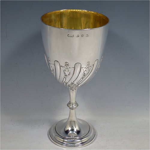 A large Antique Victorian Sterling Silver goblet, having a round tapering body with hand-chased half-fluted swirl and floral decoration, sitting on a pedestal foot, and with a gold-gilt interior. Made by Elkington & co., of Birmingham in 1894. The dimensions of this fine hand-made antique silver goblet are height 21.5 cms (8.5 inches), diameter at lip 10 cms (4 inches), and it weighs approx. 242g (7.8 troy ounces).    