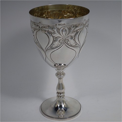 A large Antique Edwardian Sterling Silver Art Nouveau style goblet, having a round tapering body with hand-chased anthemion leaf work and plain tear-drop shaped cartouches, sitting on a pedestal foot with a bead border, and with a gold-gilt interior. Made by the Cooper Brothers of Sheffield in 1904. The dimensions of this fine hand-made antique silver Art Nouveau goblet are height 20 cms (8 inches), diameter at lip 10 cms (4 inches), and it weighs approx. 285g (9.2 troy ounces).    