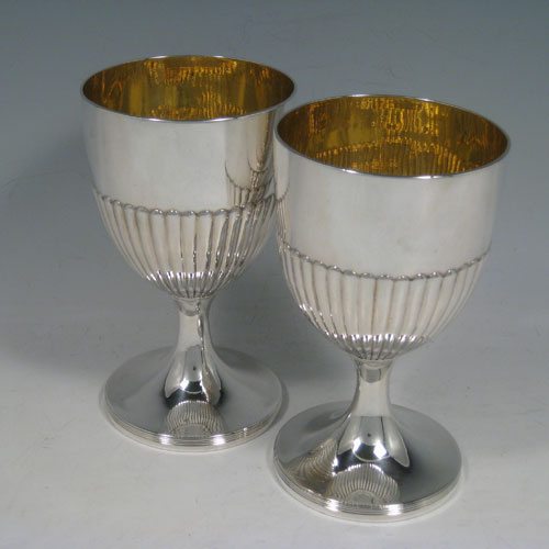 Antique Georgian sterling silver pair of goblets, having round bodies with hand-chased half-fluted decoration, gold-gilt interiors, and sitting on pedestal feet with reeded borders. Made by John Robins of London in 1803. The dimensions of this fine hand-made pair of silver goblets are height 16 cms (6.3 inches), diameter at top 9 cms (3.5 inches), and the total weight is approx. 517g (16.7 troy ounces).   