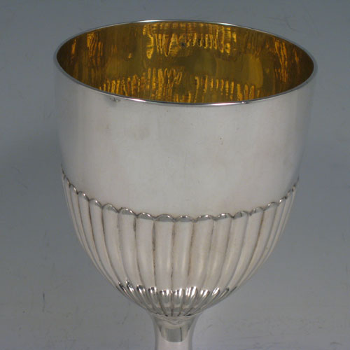 Antique Georgian sterling silver pair of goblets, having round bodies with hand-chased half-fluted decoration, gold-gilt interiors, and sitting on pedestal feet with reeded borders. Made by John Robins of London in 1803. The dimensions of this fine hand-made pair of silver goblets are height 16 cms (6.3 inches), diameter at top 9 cms (3.5 inches), and the total weight is approx. 517g (16.7 troy ounces).   