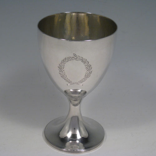 Antique Georgian sterling silver pair of goblets, having plain round bodies sitting on pedestal feet with reeded borders, and vacant laurel leaf cartouches. Made by Soloman Hougham of London in 1802 and presented in a satin and velvet-lined display box. The dimensions of this fine hand-made pair of silver goblets are height 15 cms (6 inches), diameter at top 9 cms (3.5 inches), and the total weight is approx. 445g (14.4 troy ounces).