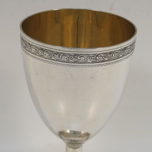 A very pretty Antique Georgian Sterling Silver goblet, having a round tapering body with a top band of hand-engraved floral and scroll decoration, sitting on a pedestal foot with a reeded border and matching engraving, and with a gold-gilt interior. This beautiful antique silver goblet was made John Emes of London in 1804. The dimensions of this fine hand-made antique silver goblet are height 14 cms (5.5 inches), diameter at lip 8 cms (3 inches), and it weighs approx. 158g (5 troy ounces).   