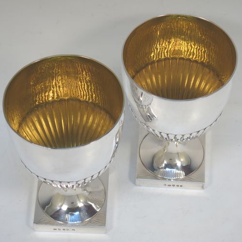 A very fine and handsome Antique Georgian Sterling Silver pair of goblets, having round bodies with hand-chased half-fluted decoration, gold-gilt interiors, and sitting on pedestal feet with square bases. Made by John Wakelin and Robert Garrard of London in 1796. The dimensions of this fine hand-made pair of antique silver goblets are height 15 cms (6 inches), diameter at top 9.5 cms (3.75 inches), and their total weight is approx. 509g (16.5 troy ounces).  