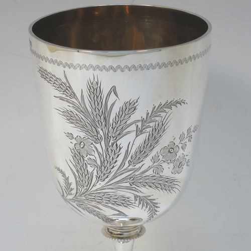 A very pretty Antique Victorian Sterling Silver goblet, having a round straight-sided and bellied body with hand-engraved floral and wheat-sheaf decoration, with a vacant cartouche on one side, a gold-gilt interior, and sitting on a pedestal foot with hand-engraved decoration and an applied bead-edged border. Made by George Maudsley Jackson of London in 1892. The dimensions of this fine hand-made antique silver goblet are height 18.5 cms (7.3 inches), diameter at lip 8.5 cms (3.3 inches), and it weighs approx. 175g (5.6 troy ounces).  