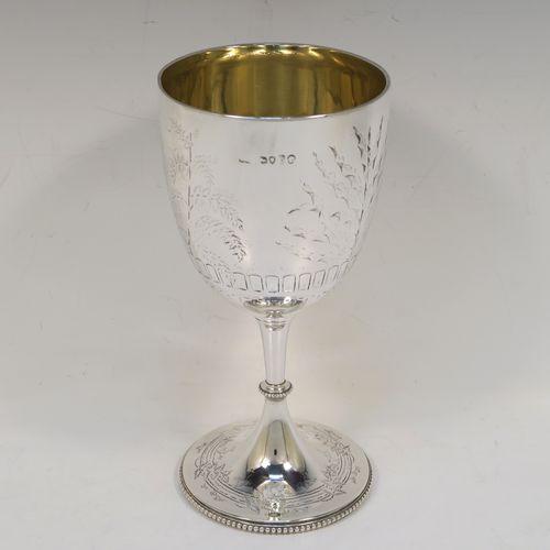 A very pretty Antique Victorian Sterling Silver goblet, having a round straight-sided and bellied body with hand-engraved floral and fern decoration, a gold-gilt interior, and sitting on a pedestal foot with hand-engraved decoration and an applied bead-edged border. This beautiful antique silver goblet was made by Frederick Elkington of London in 1873. The dimensions of this fine hand-made antique silver goblet are height 18.5 cms (7.25 inches), diameter at lip 9 cms (3.5 inches), and it weighs approx. 205g (6.6 troy ounces).   