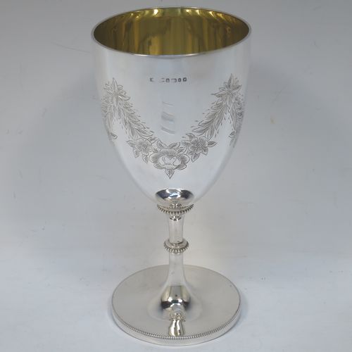 A very pretty Antique Victorian Sterling Silver goblet, having a round bellied body with hand-engraved swags of floral decoration, a gold-gilt interior, and sitting on a pedestal foot with an applied bead-edged border. Made by James Dixon and Sons of Sheffield in 1877. The dimensions of this fine hand-made antique silver goblet are height 18 cms (7 inches), diameter at lip 8.5 cms (3.3 inches), and it weighs approx. 224g (7.2 troy ounces).  