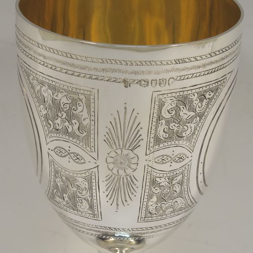 A large and very pretty Antique Victorian Sterling Silver goblet, having a round tapering body with hand-engraved floral and scroll decoration surrounding two round vacant cartouches on either side, sitting on a pedestal foot with applied bead-edged borders, and with a gold-gilt interior. This beautiful antique silver wine goblet was made by Charles Stuart Harris of London in 1887. The dimensions of this fine hand-made antique silver goblet are height 18.5 cms (7.25 inches), diameter at lip 8.5 cms (3.3 inches), and it weighs approx. 224g (7.2 troy ounces).