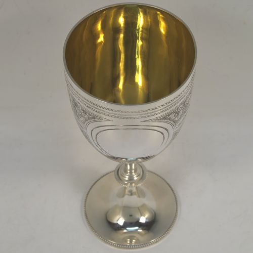 A large and very pretty Antique Victorian Sterling Silver goblet, having a round tapering body with hand-engraved floral and scroll decoration surrounding two round vacant cartouches on either side, sitting on a pedestal foot with applied bead-edged borders, and with a gold-gilt interior. This beautiful antique silver wine goblet was made by Charles Stuart Harris of London in 1887. The dimensions of this fine hand-made antique silver goblet are height 18.5 cms (7.25 inches), diameter at lip 8.5 cms (3.3 inches), and it weighs approx. 224g (7.2 troy ounces).