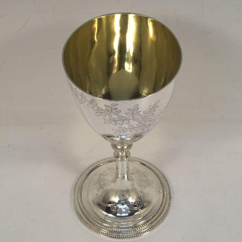 A very pretty Antique Victorian Sterling Silver goblet, having a round bellied body with hand-engraved tree and leaf floral decoration, a gold-gilt interior, and sitting on a pedestal foot with an applied double bead-edged border. This beautiful silver goblet was made by Thomas Smiley of London in 1870. The dimensions of this fine hand-made antique silver goblet are height 16.5 cms (6.5 inches), diameter at lip 8 cms (3.25 inches), and it weighs approx. 172g (5.5 troy ounces).   