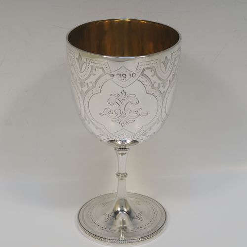 A pretty Antique Victorian Sterling Silver goblet, having a round bellied body with hand-engraved floral and scroll decoration, a gold-gilt interior, and sitting on a pedestal foot with hand-engraved decoration and an applied bead-edged border. This beautiful silver goblet was made by Henry Holland of London in 1870. The dimensions of this fine hand-made antique silver goblet are height 16.5 cms (6.5 inches), diameter at lip 8.5 cms (3.3 inches), and it weighs approx. 188g (6 troy ounces).   