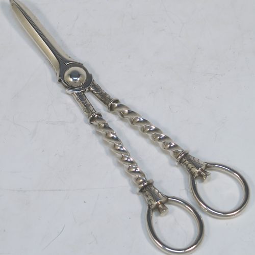 A very pretty Antique Victorian Sterling Silver pair of grape shears or scissors, with cast handles in a twisted style, with plain loop handles and hand-chased terminals, all in its original maroon velvet and stain-lined presentation box. This beautiful pair of antique silver grape scissors were made by Edward Hutton  of London in 1889. The dimensions of this fine hand-made pair of antique silver grape shears are length 17.5 cms (7 inches), and they weigh approx. 109g (3.5 troy ounces).  