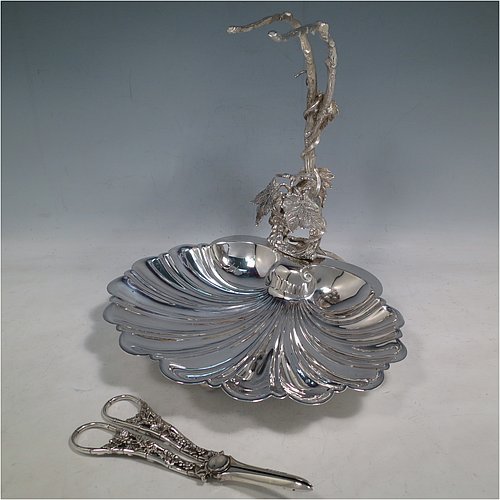 An Antique Victorian silver-plated grape dish stand with a pair of original grape shears in the Grapevine pattern, with cast vine-leaf tendrils, and a shell-style dish, sitting on three ball feet. All made by William Hutton & Sons of Sheffield in ca. 1880. The dimensions of this fine hand-made antique silver plated grape dish stand and scissors are height 27 cms (10.5 inches), width 25.5 cms (10 inches), and length 25.5 cms (10 inches).   