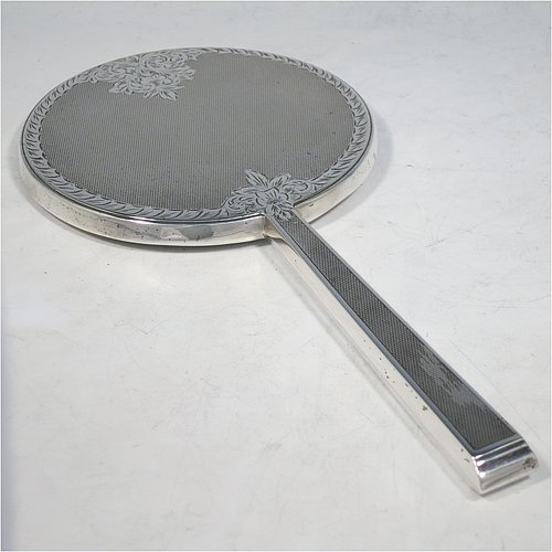 A Sterling Silver hand-mirror, having a round body and a square cross-section handle, with engine-turned decoration and a very pretty hand-engraved floral border, and an original round bevelled mirror. Made by Broadway & Co., of Birmingham in 1971. The dimensions of this fine hand-made silver hand mirror are length 25.5 cms (10 inches), and diameter of mirror 12.5 cms (5 inches).   