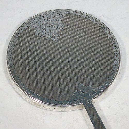 A Sterling Silver hand-mirror, having a round body and a square cross-section handle, with engine-turned decoration and a very pretty hand-engraved floral border, and an original round bevelled mirror. Made by Broadway & Co., of Birmingham in 1971. The dimensions of this fine hand-made silver hand mirror are length 25.5 cms (10 inches), and diameter of mirror 12.5 cms (5 inches).   