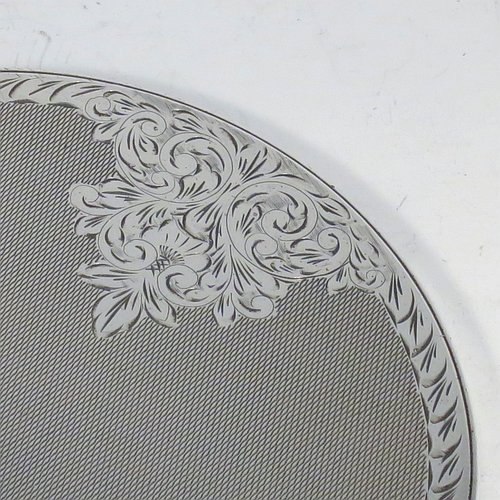 A Sterling Silver hand-mirror, having a round body and a square cross-section handle, with engine-turned decoration and a very pretty hand-engraved floral border, and an original round bevelled mirror. Made by Broadway & Co., of Birmingham in 1971. The dimensions of this fine hand-made silver hand mirror are length 25.5 cms (10 inches), and diameter of mirror 12.5 cms (5 inches).   