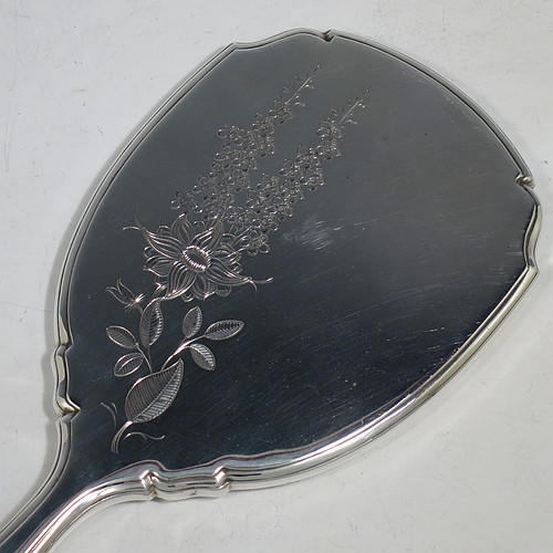 A very pretty Sterling Silver hand-mirror, having a shaped rectangular body with reeded borders, a hand-engraved back with floral decoration, and an original bevelled mirror. Made by Deakin and Francis of Birmingham in 1966. The dimensions of this fine hand-made silver hand mirror are length 26 cms (10.25 inches), and width 10 cms (4 inches).    