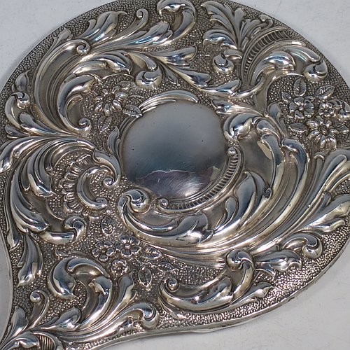 An Antique Edwardian Sterling Silver hand-mirror, having a round body with hand-chased floral decoration, a central vacant cartouche on the main body and an oval cartouche on the handle, and a round mirror. Made by William Neale of Chester in 1906. The dimensions of this fine hand-made antique silver hand mirror are length 28 cms (11 inches), and diameter 15 cms (6 inches).   