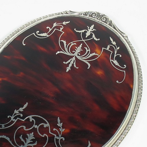 A Sterling Silver and Tortoise-shell hand-mirror, having an oval body with an applied floral border, with very pretty Neoclassical style inlaid tortoiseshell decoration, and an original bevelled mirror. Made by Mappin and Webb of Birmingham in 1928. The dimensions of this fine hand-made silver and tortoise-shell hand mirror are length 28 cms (11 inches), and width of mirror 11 cms (4.25 inches).    