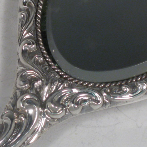 Antique Victorian sterling silver hand-mirror, having an oval body with hand-chased floral decoration and cherub, a central vacant cartouche, and an oval bevelled mirror with rope-twist border. Made by Henry Hayes of Birmingham in 1898. The dimensions of this fine hand-made silver hand mirror are length 26 cms (10 inches), and width 10 cms (4 inches). Please note that the mirror surface shows signs of very slight clouding. 