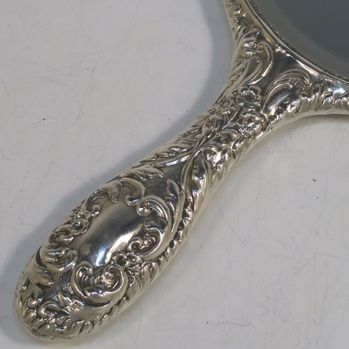 A very pretty Sterling Silver hand-mirror, having a round body with hand-chased floral border surrounding a group of winged cherub faces, and a round bevelled mirror with rope-twist border. This beautiful silver hand mirror was made in Birmingham in 1981. The dimensions of this fine hand-made silver hand mirror are length 23.5 cms (9.25 inches), and diameter of main body 12.5 cms (5 inches).