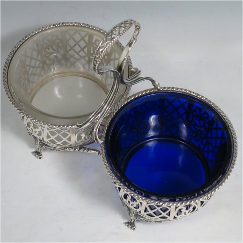 An Antique Edwardian Sterling Silver preserve, jam and honey pot holder, having a blue and frosted glass pot, sitting in a hand-pierced frame with floral and geometric decoration, with applied gadroon borders, a reeded and pierced loop handle, and all sitting on four cast floral feet. Made by Mappin and Webb of London in 1907. The dimensions of this fine hand-made antique silver and glass preserve holder are length 21 cms (8.25 inches), width 11 cms (4.25 inches), height 17.5 cms (7 inches),  and it weighs approx. 243g (7.8 troy ounces).   