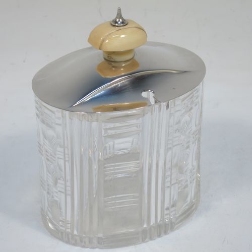 An elegant and stylish Art Deco Sterling Silver and hand-cut crystal jam, honey, or preserve jar, having a plain oval pull-off lid with matching bone finial and a slot for a spoon, and a hand-cut crystal body with reeded decoration and flat base. Made by Frank Cobb of Sheffield in 1936. The dimensions of this fine hand-made Art Deco silver and crystal jar are height 10 cms (4 inches), width 8 cms (3.25 inches), and depth 6.5 cms (2.5 inches)..  