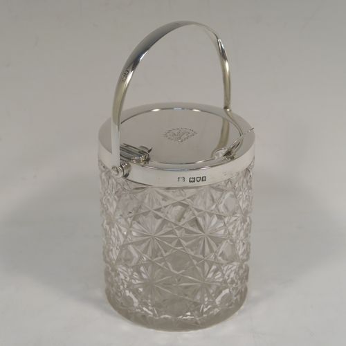 A very handsome Antique Victorian Sterling Silver and crystal honey or jam jar, having a hobnail and star-cut cylindrical crystal body with a star-cut base, a plain round mount with a mechanical swing-handled hinged lid, and an original spoon. This beautiful antique silver jam or honey jar was made by Heath and Middleton of London in 1901. The dimensions of this fine hand-made antique silver and crystal jam or honey jar are height (inc. handle) 14 cms (5.5 inches), and diameter 8 cms (3 inches). Please note that this item is crested.  