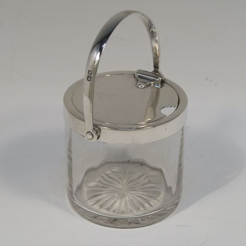 A very elegant Antique Edwardian Sterling Silver and crystal honey or jam jar, having a plain cylindrical and panelled body with star-cut base, a plain round mount, and a plain mechanical swing-handled hinged lid. This handsome silver honey or jam jar was made by Heath and Middleton of London in 1903. The dimensions of this fine hand-made antique silver and crystal conserve jar are height (inc. handle) 11 cms (4.25 inches), and diameter 7 cms (2.75 inches).   