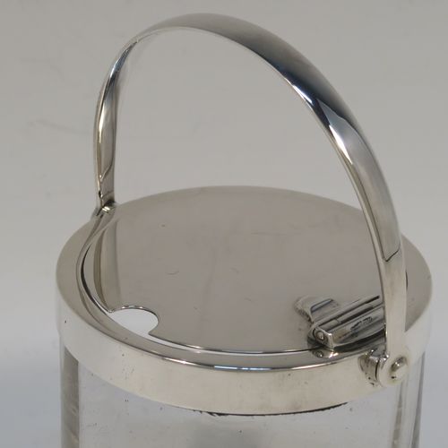 A very elegant Antique Edwardian Sterling Silver and crystal honey or jam jar, having a plain cylindrical and panelled body with star-cut base, a plain round mount, and a plain mechanical swing-handled hinged lid. This handsome silver honey or jam jar was made by Heath and Middleton of London in 1903. The dimensions of this fine hand-made antique silver and crystal conserve jar are height (inc. handle) 11 cms (4.25 inches), and diameter 7 cms (2.75 inches).   