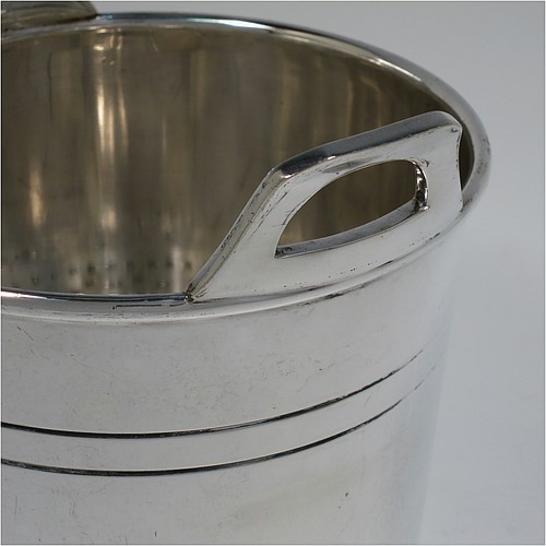 An Antique Edwardian silver plated ice bucket, having a plain round body with tapering straight sides and hand-chased reeded decoration, an internal removable dry ice drainer, with two top cast side handles, and all sitting on a flat base. Made by Collins of London in ca. 1910. The dimensions of this fine hand-made antique silver-plated ice bucket are height 15.5 cms (6 inches), and diameter at lip 14 cms (5.5 inches).   