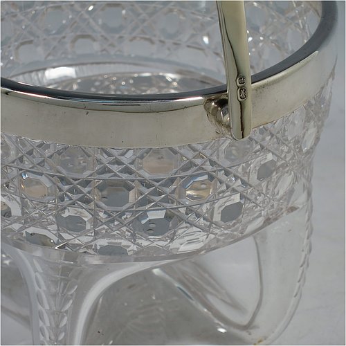 An Antique Victorian Sterling Silver and hand-cut crystal ice bucket, having a round hob-nail cut crystal body sitting on four unusual conjoined legs, with an internal removable dry ice drainer, a plain silver rim, and a hinged swing handle. Made by the Henry Williamson Ltd., of Birmingham in 1900. The dimensions of this fine hand-made antique silver and crystal ice bucket are height (excluding handle) 12.5 cms (5 inches), and diameter at lip 12.5 cms (5 inches).    