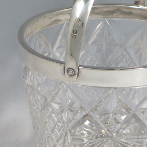 Antique Victorian sterling silver ice bucket, having a round hand-cut crystal body with tapering sides, an internal removable dry ice drainer, a plain silver rim, and a hinged swing handle. Made by the Dixon Brothers of London in 1899. The dimensions of this fine hand-made silver ice bucket are height (excluding handle) 13 cms (5 inches), and diameter at lip 13 cms (5 inches). Please note that there is a small crack in the top border that is hidden by the silver rim.