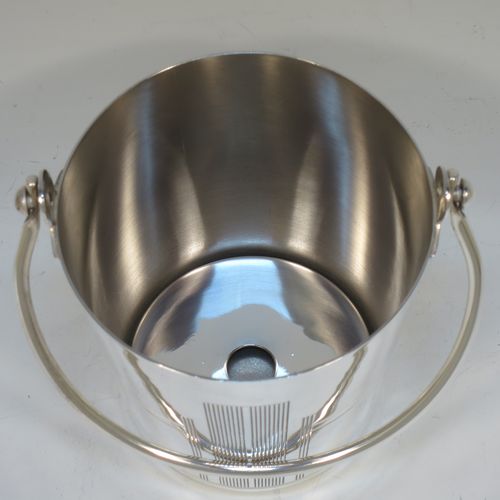 A very stylish Art Deco Silver Plated ice bucket, having a plain round body with tapering straight sides and hand-chased reeded decoration, an internal removable dry ice drainer, with a hinged loop handle, and all sitting on a flat base. Made in ca. 1930. The dimensions of this fine hand-made silver-plated ice bucket are height (not including handle) 11 cms (4.3 inches), and diameter at lip 11 cms (4.3 inches).  