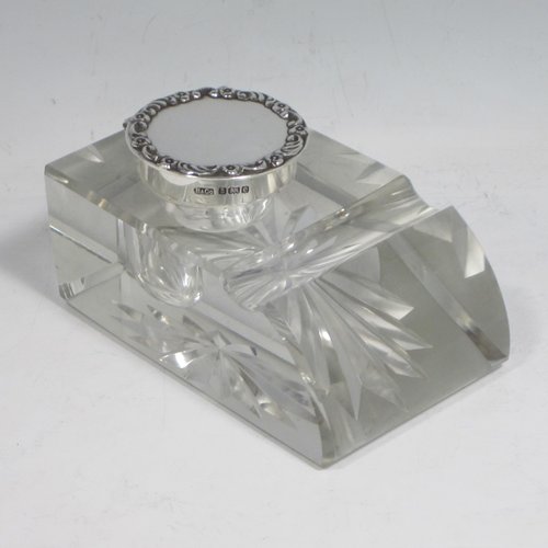 Antique Edwardian sterling silver and hand-cut crystal inkstand, having a rectangular body with chamfered corners, a pen holder groove above a curved front face, plain round silver mount with a hinged lid having an applied floral border, and all sitting on a star-cut flat base. Made by Broadway & Co., of Birmingham in 1904. The dimensions of this fine hand-made silver and crystal inkstand are height 5 cms (2 inches), length 10 cms (4 inches), and width 6.5 cms (2.5 inches).   